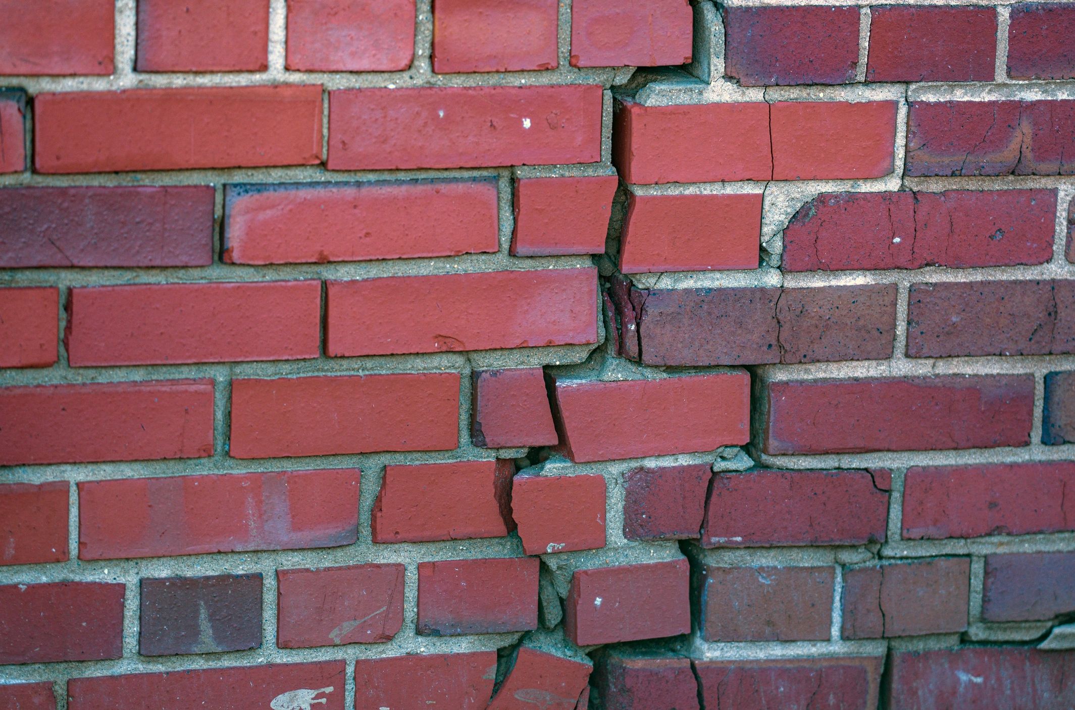 Close-up of a cracked brick wall showing mortar joints